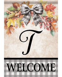 A decorative autumn-themed welcome sign with a large black script letter J, colorful fall leaves, berries, and a gray-and-white plaid bow at the top, plus a plaid banner at the bottom reading WELCOME.