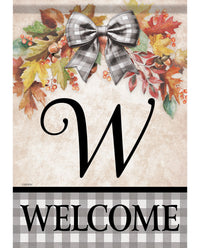 A decorative fall-themed welcome garden flag with a large black letter W, a gray-and-white plaid bow, autumn leaves, berries, acorns, and a plaid banner reading WELCOME at the bottom.