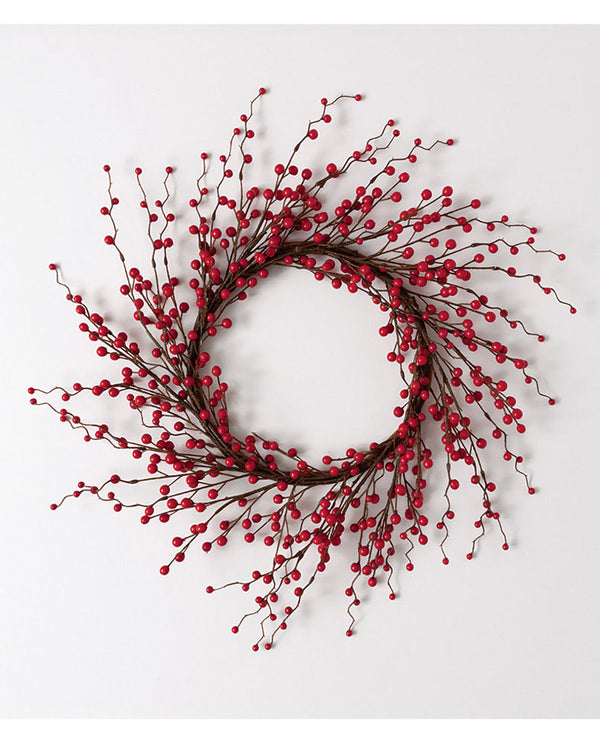 A festive holiday wreath made of dark brown branches densely covered with small, glossy red berries, displayed against a clean white background.