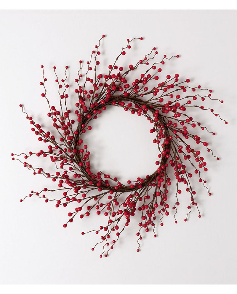 A festive holiday wreath made of dark brown branches densely covered with small, glossy red berries, displayed against a clean white background.
