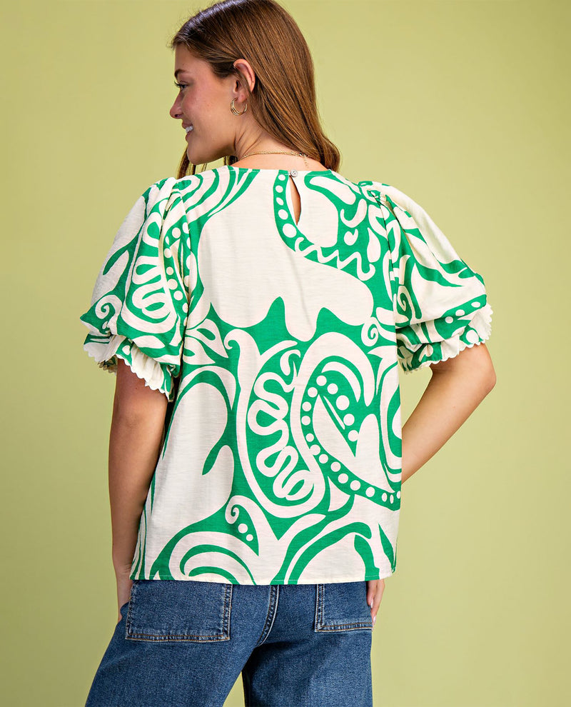 Woman wearing a green and white patterned blouse against a light green background