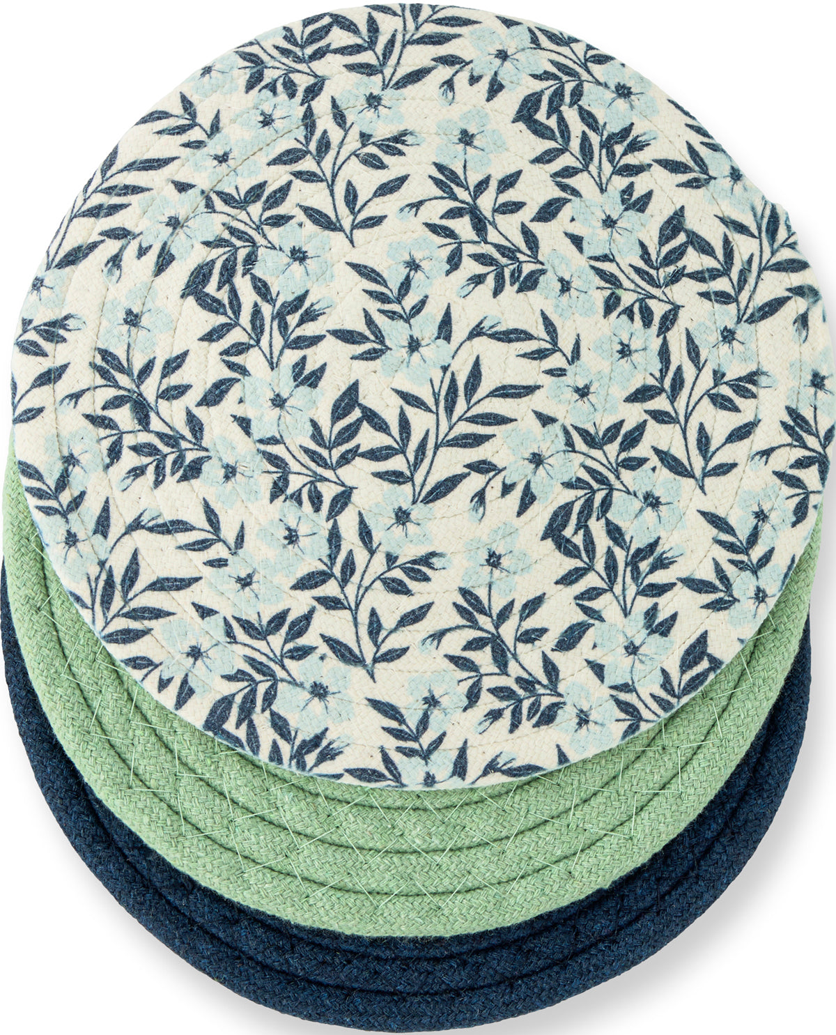 A stack of round woven placemats or coasters, with the top one featuring a navy blue floral and leaf pattern on an off-white background, and the layers underneath in solid light green and dark navy blue.