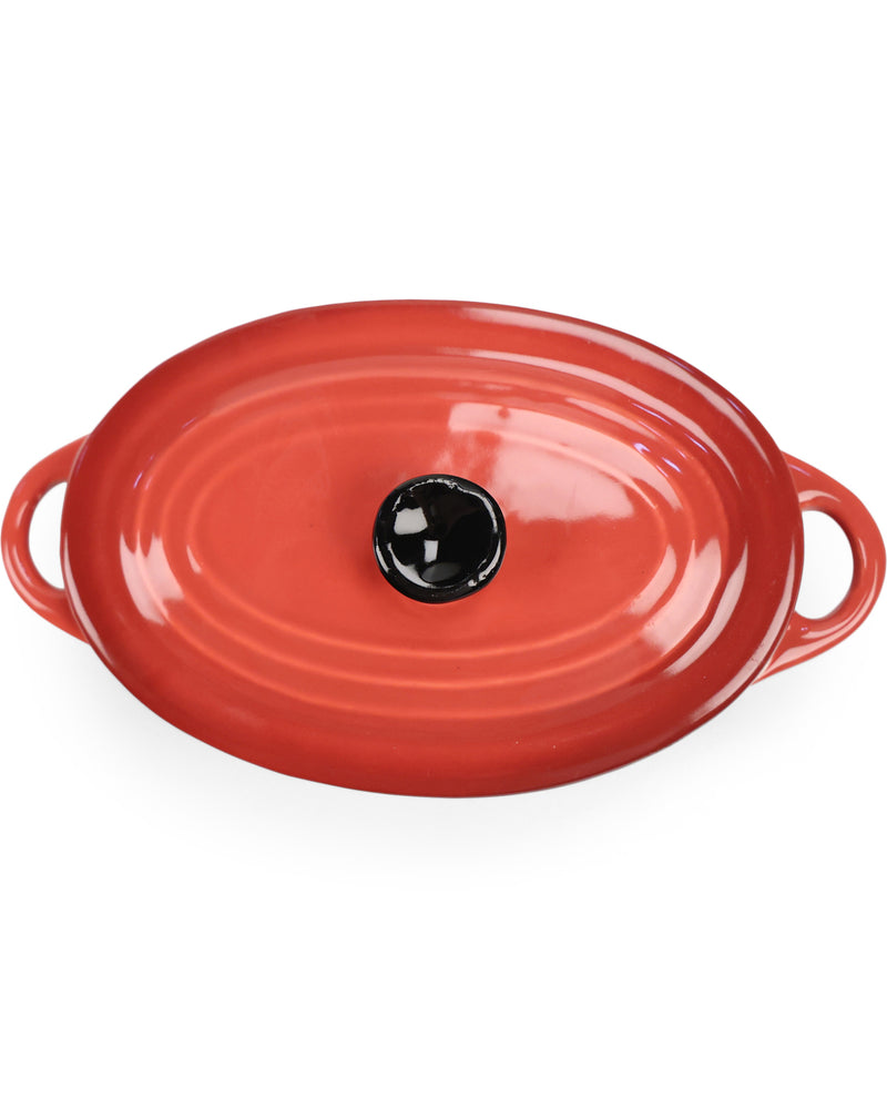 An oval red enameled cast iron casserole dish with side handles and a black knob on top, shown against a plain white background.