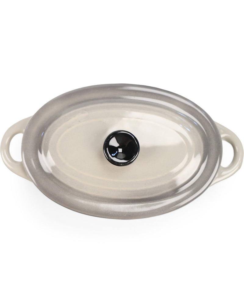 An oval glass casserole dish with a clear lid featuring a black glass knob and side handles, shown on a white background.