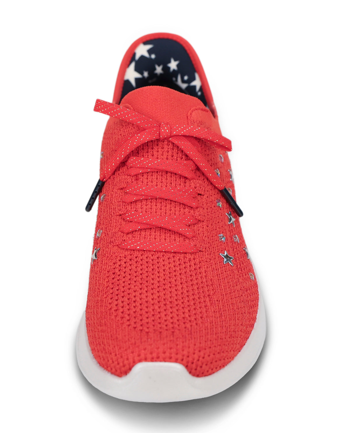 A red knit sneaker with a white sole, featuring decorative silver star embellishments on the side and a navy blue lining with white stars on the inner collar.