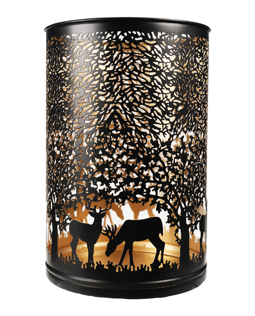 A black metal cylindrical lantern with a laser-cut forest design featuring silhouettes of trees, deer, and a warm glowing light inside, shown against a plain white background.