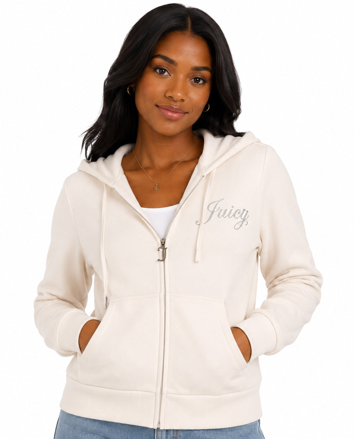 A woman wearing a cream-colored zip-up hoodie with 'Juicy' written in silver script on the left chest, paired with a white tank top and blue jeans, set against a plain white background.