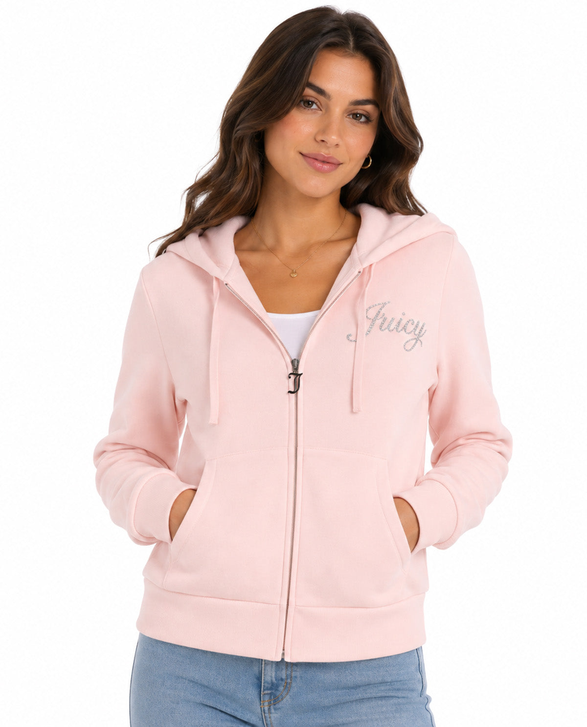 A woman wearing a light pink zip-up hoodie with 'Juicy' written in silver script on the left chest, paired with a white tank top and blue jeans, against a plain white background.