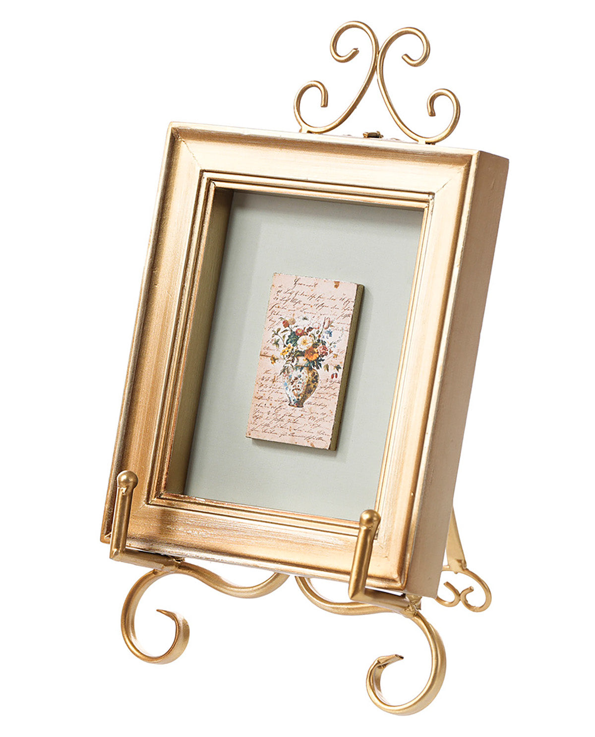 A gold-colored metal picture frame with an easel stand base and decorative scrollwork on the top and bottom, holding a small floral card, shown on a white background.