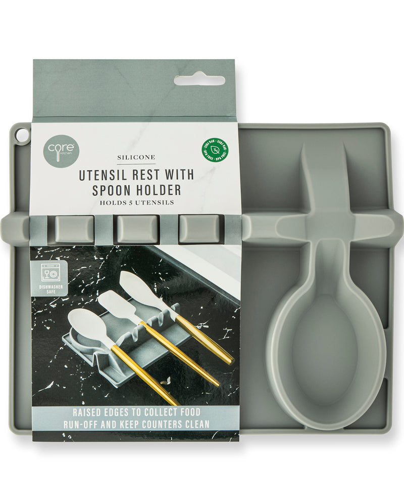 Core 7 Silicone Utensil Rest with Spoon Holder in a muted gray-green color, shown both inside its retail packaging and unpackaged. The packaging features a white and gray header card with product details and a lifestyle graphic of gold utensils on a black marble surface.