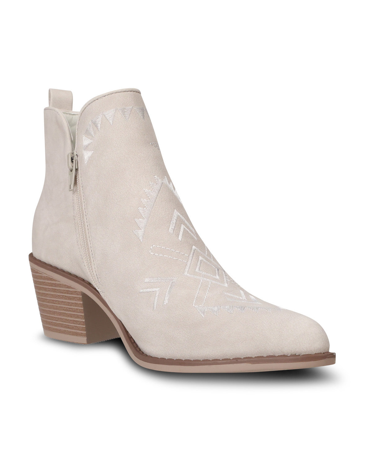 A light beige suede ankle boot with a low block heel, side zipper, and white geometric embroidered patterns on the side, shown against a plain white background.