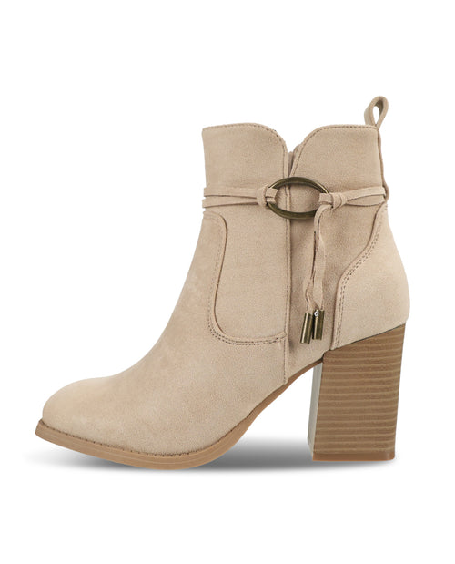 A beige suede ankle boot with a block heel, featuring a decorative strap with a metal ring and tassel detail on the side, shown against a plain white background.