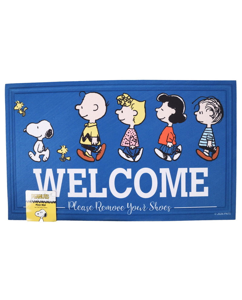 A blue rectangular doormat featuring the Peanuts characters Snoopy, Woodstock, Charlie Brown, Lucy, Sally, and Linus walking under the word 'WELCOME' in large white letters, with the phrase 'Please Remove Your Shoes' below. A small retail tag is attached to the lower left corner.