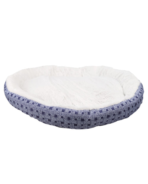 An oval-shaped pet bed with a white plush fleece interior and a navy blue and white geometric patterned fabric exterior, shown against a plain white background.