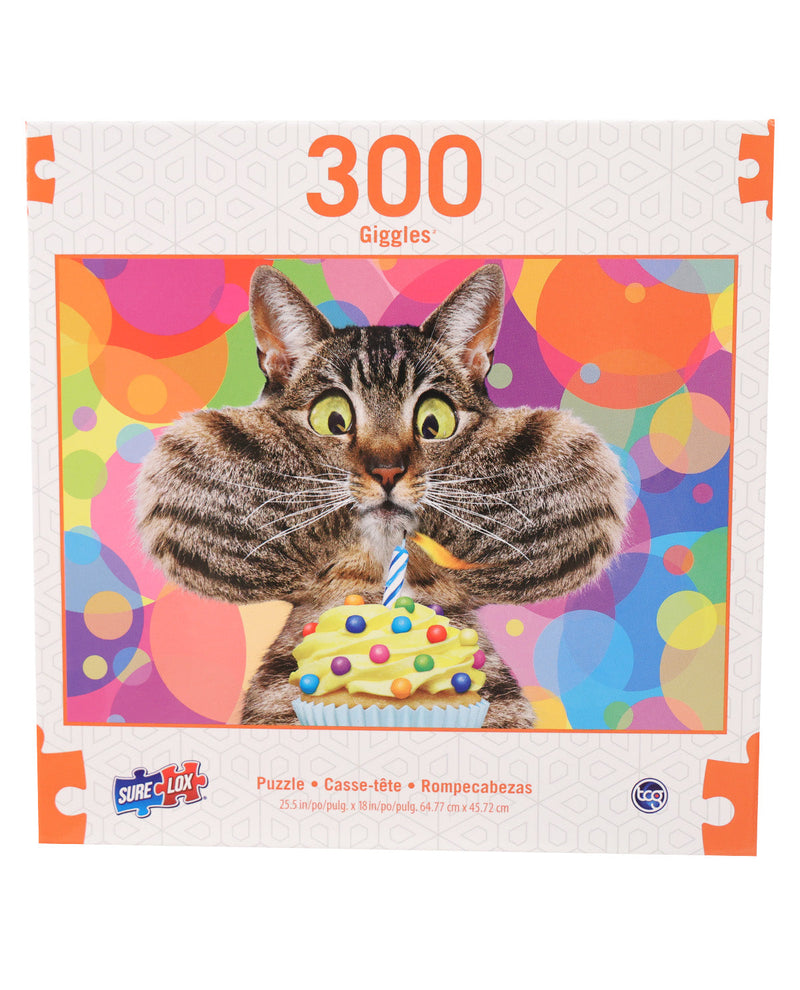 A 300-piece jigsaw puzzle box titled 'Giggles' featuring a funny photo of a tabby cat with wide eyes holding a cupcake in front of a colorful party background. The Sure! Luv! brand logo is visible in the bottom left corner.