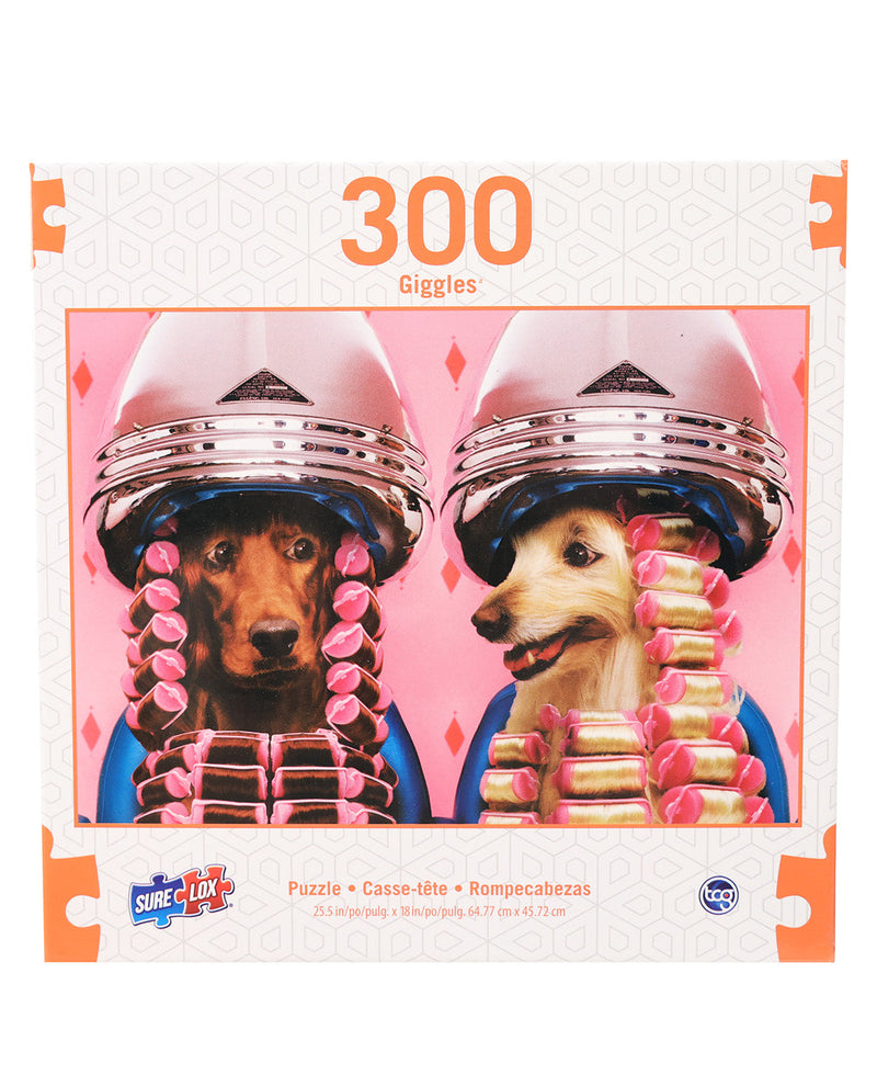 A 300-piece jigsaw puzzle box titled '300 Giggles' featuring two dogs wearing metallic silver helmets and pink-and-gold bullet-shaped hair accessories against a pink background.