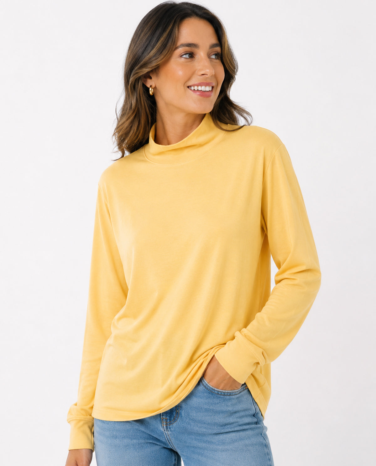 Woman wearing a yellow long-sleeve top and blue jeans on a white background