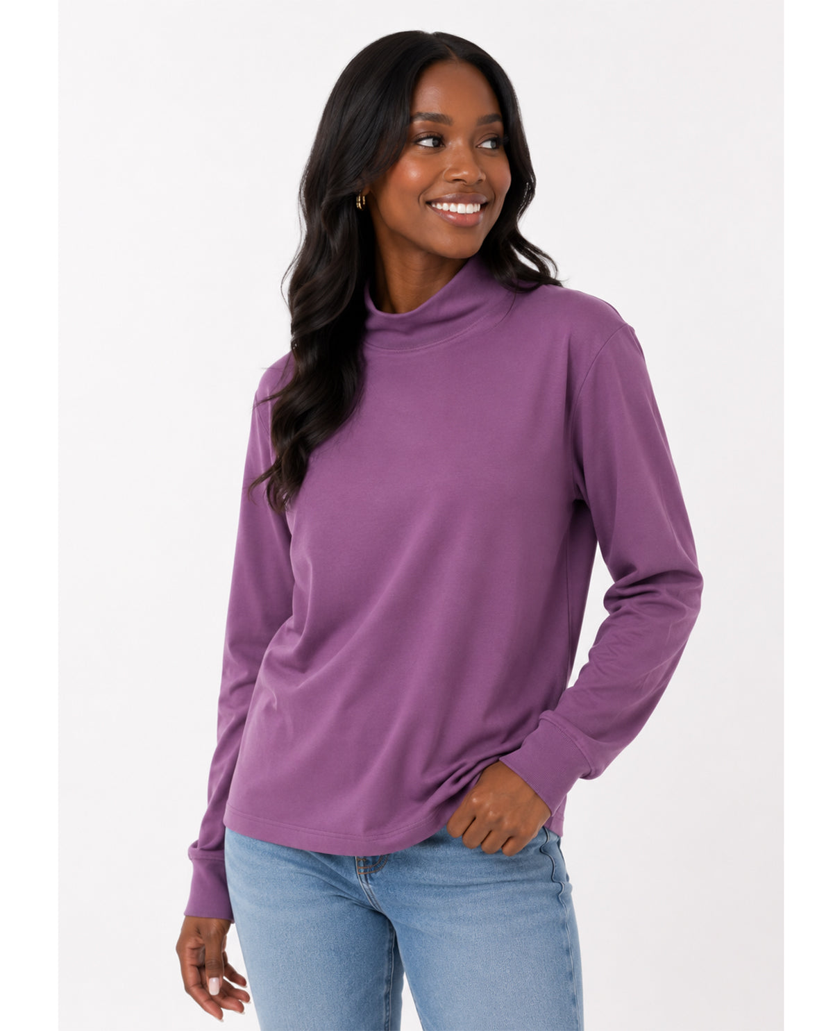 Woman wearing a purple long-sleeve top and light blue jeans on a white background