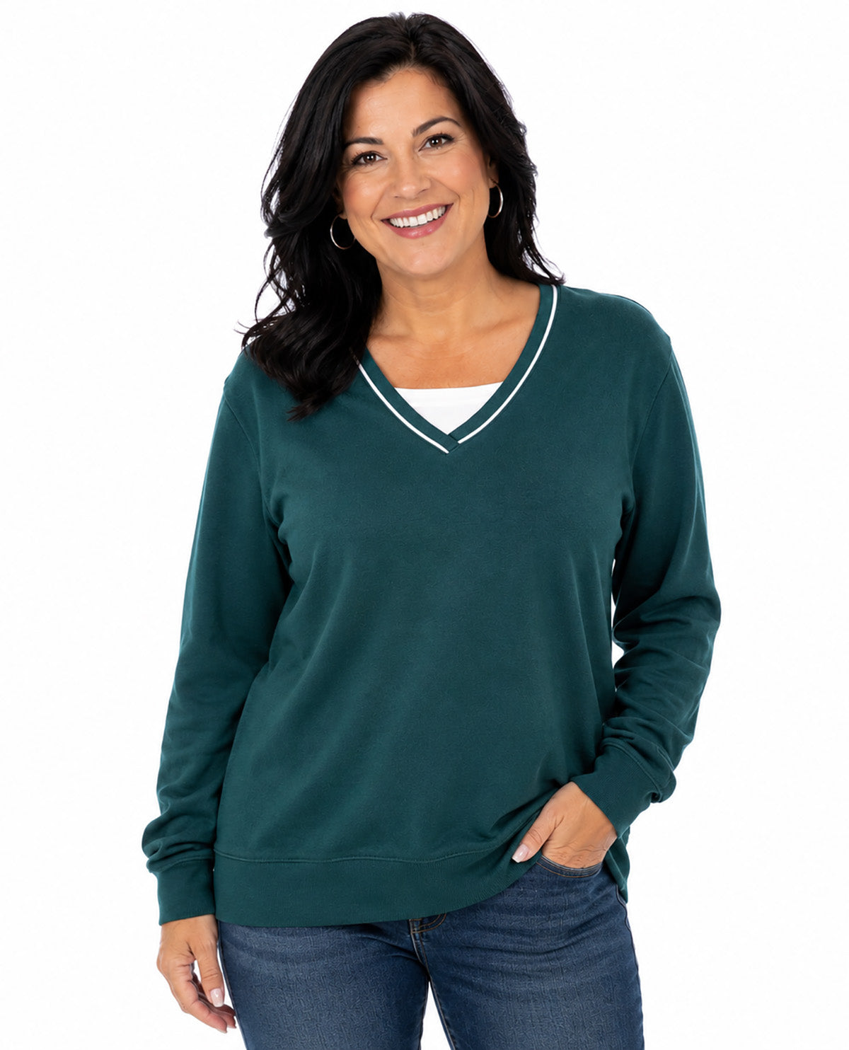 A woman wearing a dark green long-sleeve V-neck sweater with white trim, paired with blue jeans, against a plain white background.
