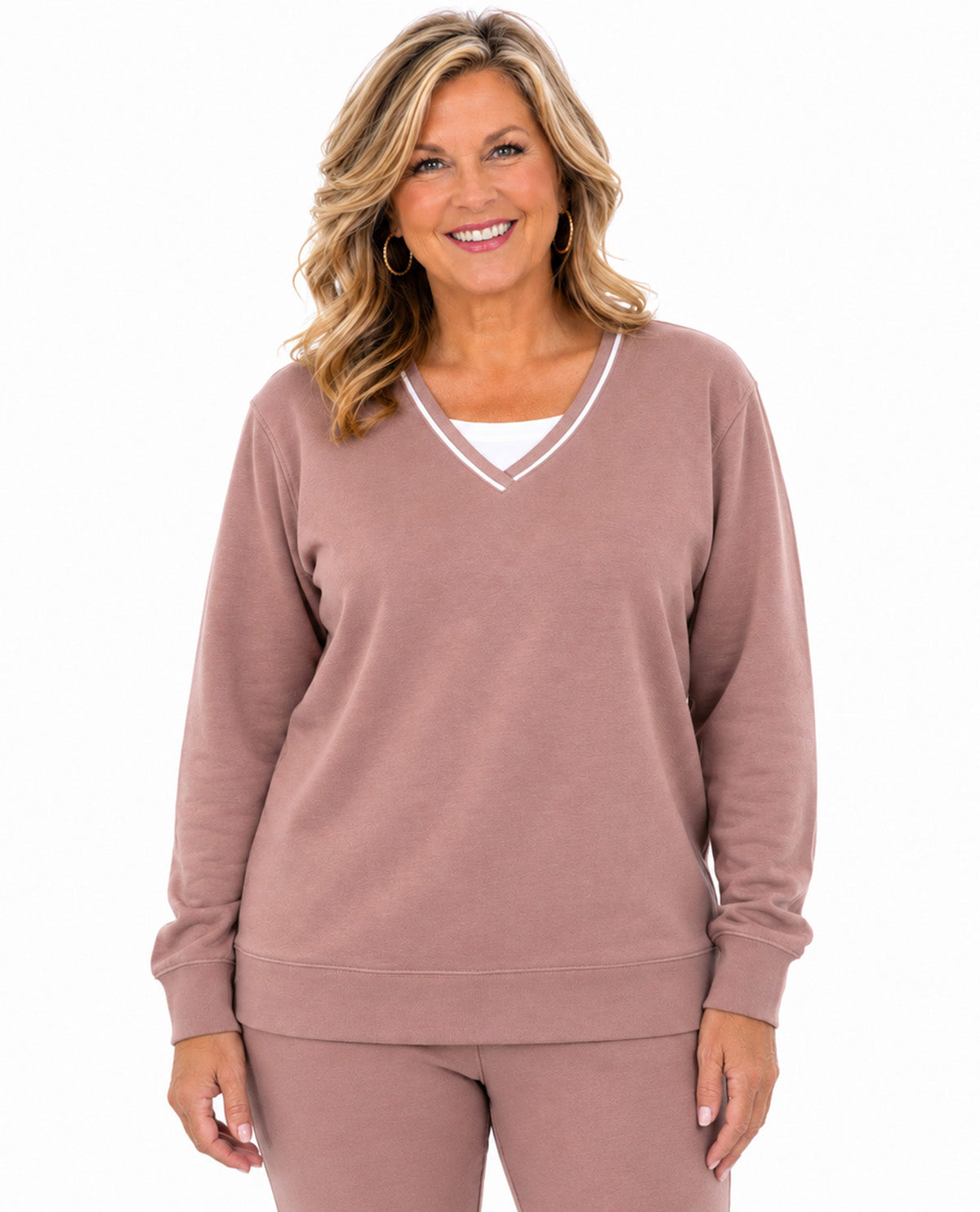 A woman modeling a dusty rose long-sleeve V-neck sweatshirt with white contrast trim, paired with matching sweatpants, against a plain white background.
