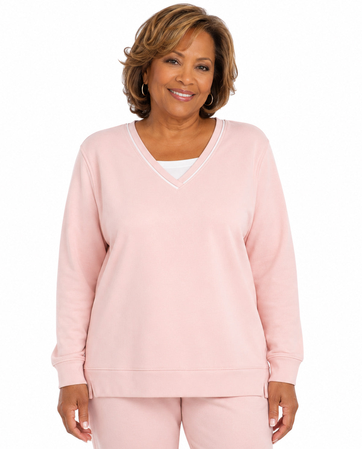 A woman modeling a light pink long-sleeve V-neck sweatshirt and matching sweatpants against a plain white background.