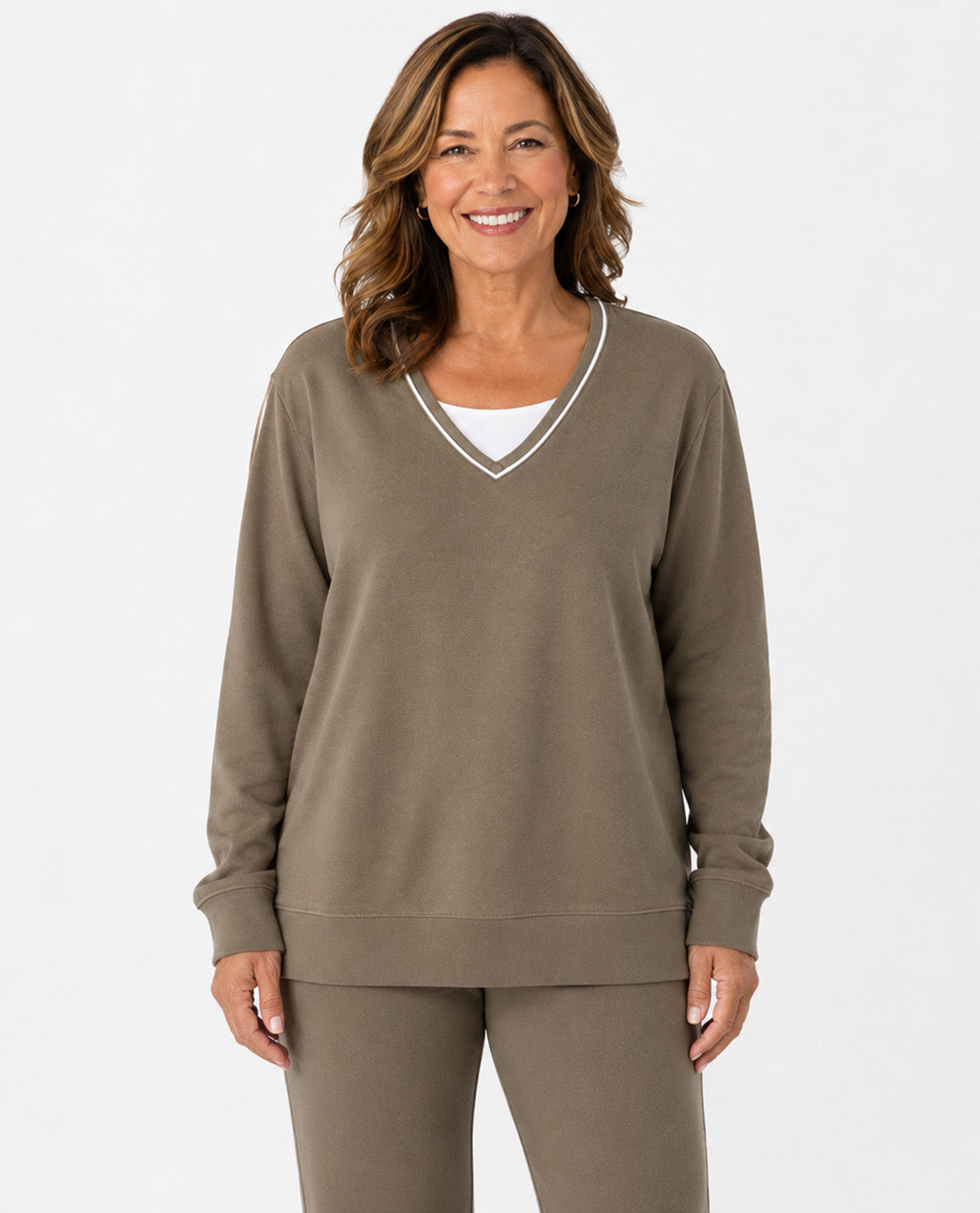 A smiling woman wearing a taupe brown long-sleeve V-neck sweatshirt with white trim and matching sweatpants, photographed against a clean white studio background.