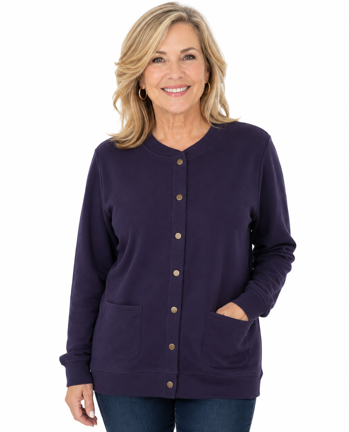A smiling blonde woman wearing a dark purple long-sleeve button-front cardigan with front pockets, paired with blue jeans, against a plain white background.