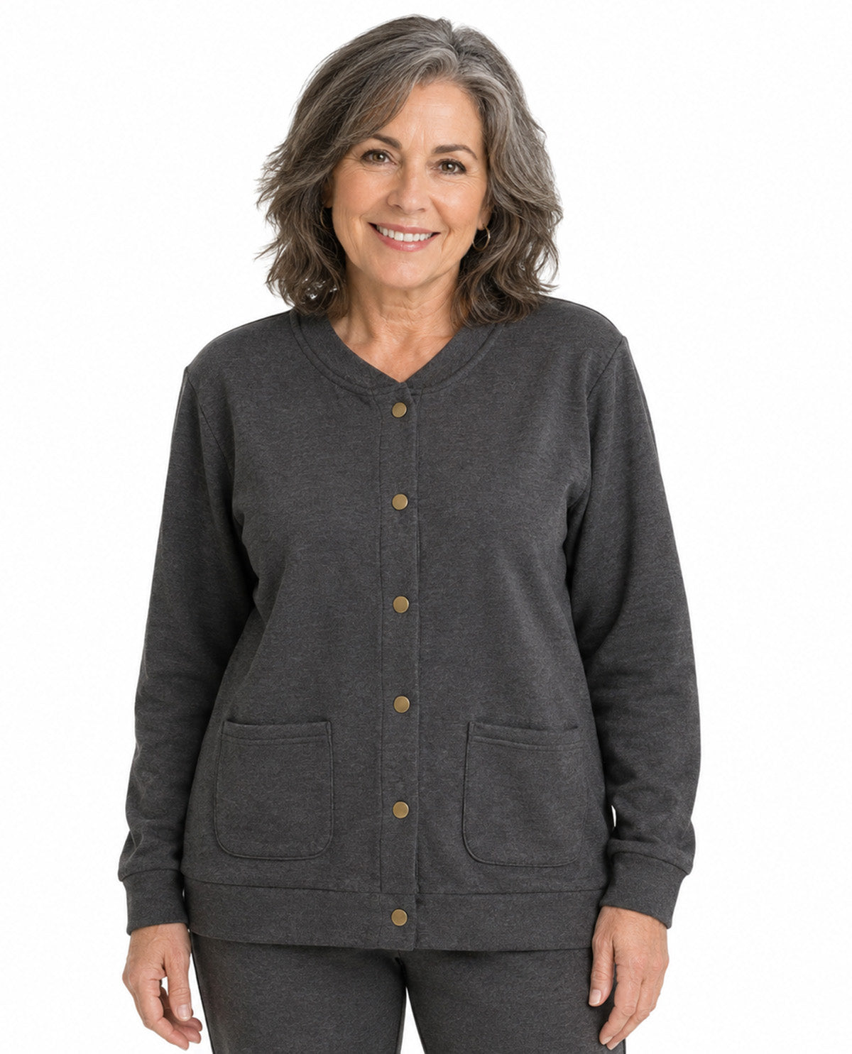 A smiling woman with shoulder-length gray hair wearing a dark charcoal gray button-up cardigan with brown buttons and two front patch pockets, paired with matching gray pants, against a plain white background.