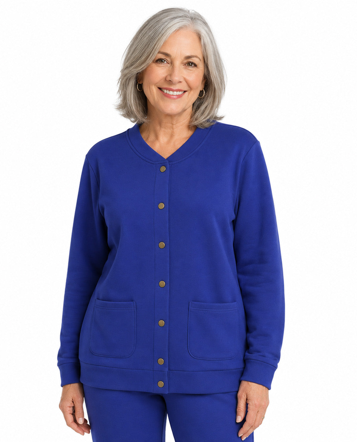 A smiling woman with short gray hair wearing a royal blue button-front cardigan and matching blue pants, photographed against a plain white studio background.
