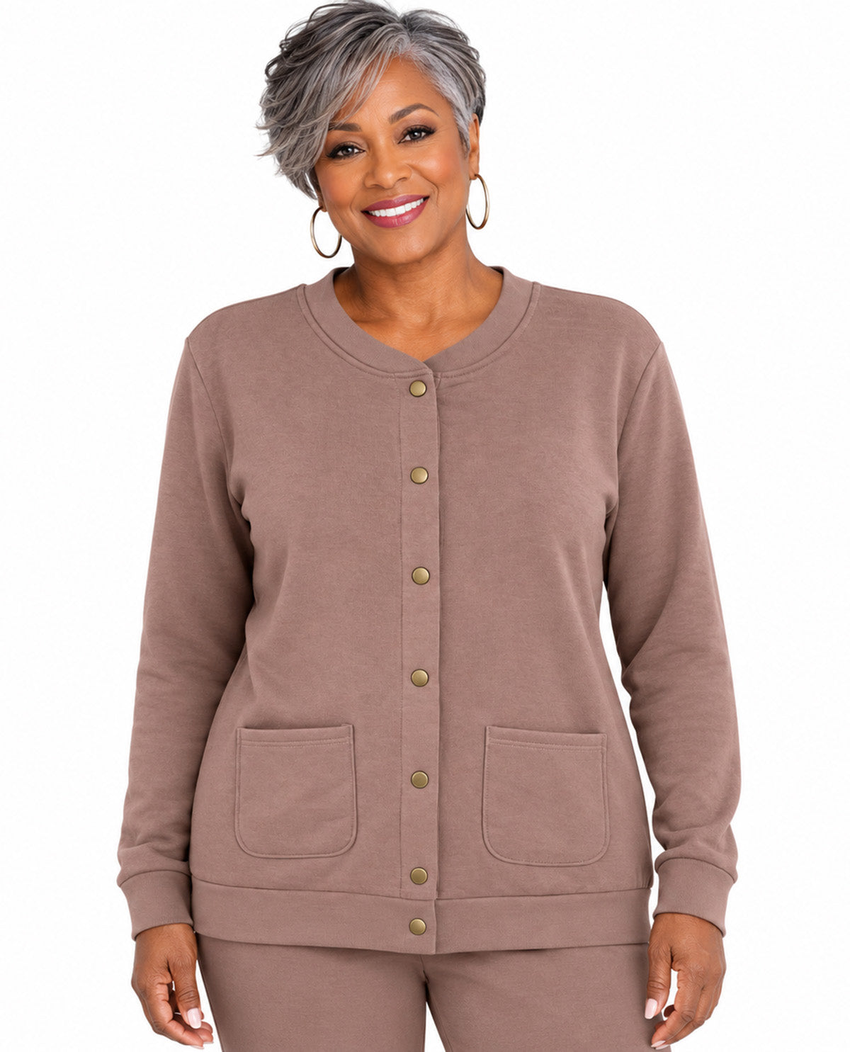 A woman with short gray hair wearing a taupe-brown long-sleeve button-front cardigan with two front patch pockets and matching pants, photographed against a plain white background.
