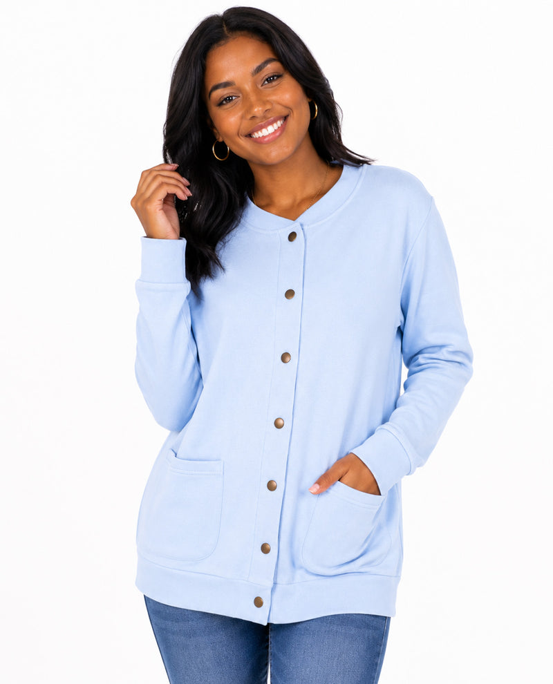 A woman wearing a light blue long-sleeve button-front cardigan with front pockets, paired with blue jeans, against a plain white background.