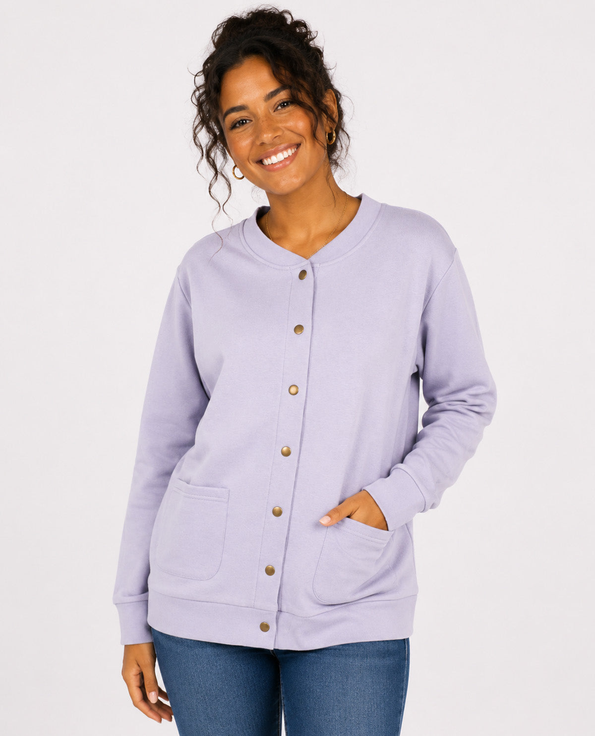 A woman wearing a light lavender cardigan with a button-down front, ribbed collar, and front pockets, paired with blue jeans against a plain white background.