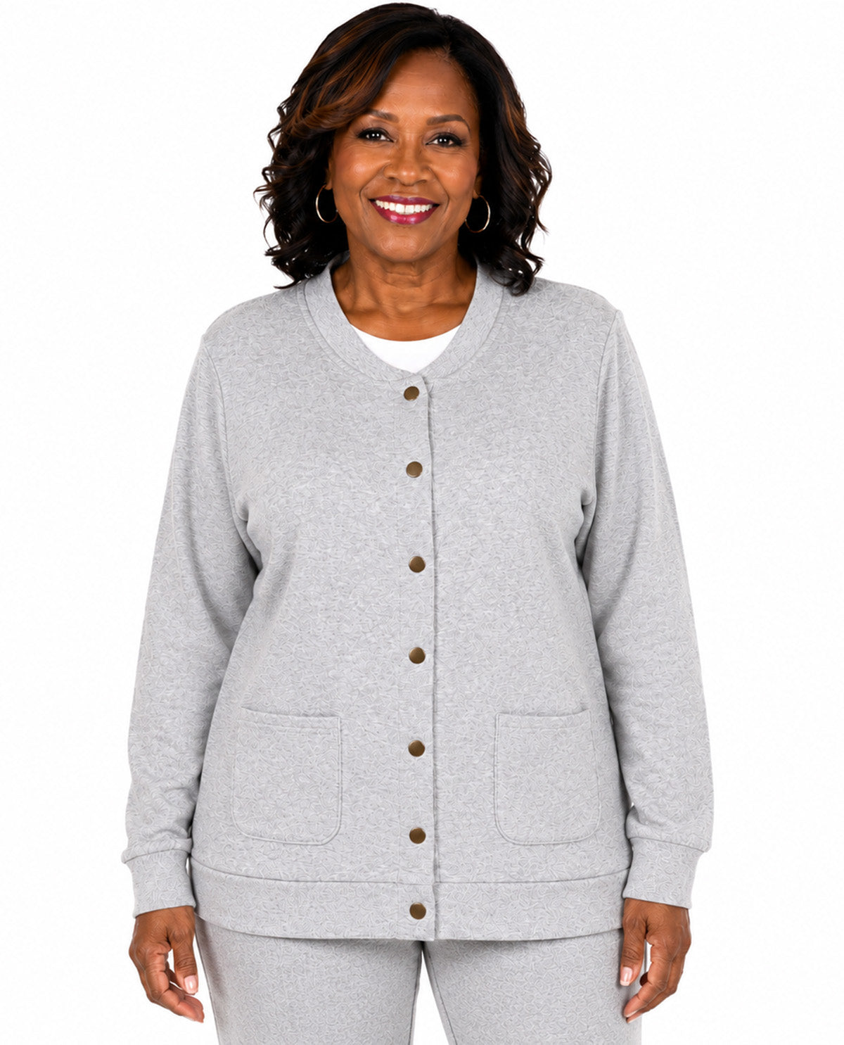 A smiling woman wearing a light gray heather button-front cardigan with two front patch pockets and matching gray pants, photographed against a plain white studio background.