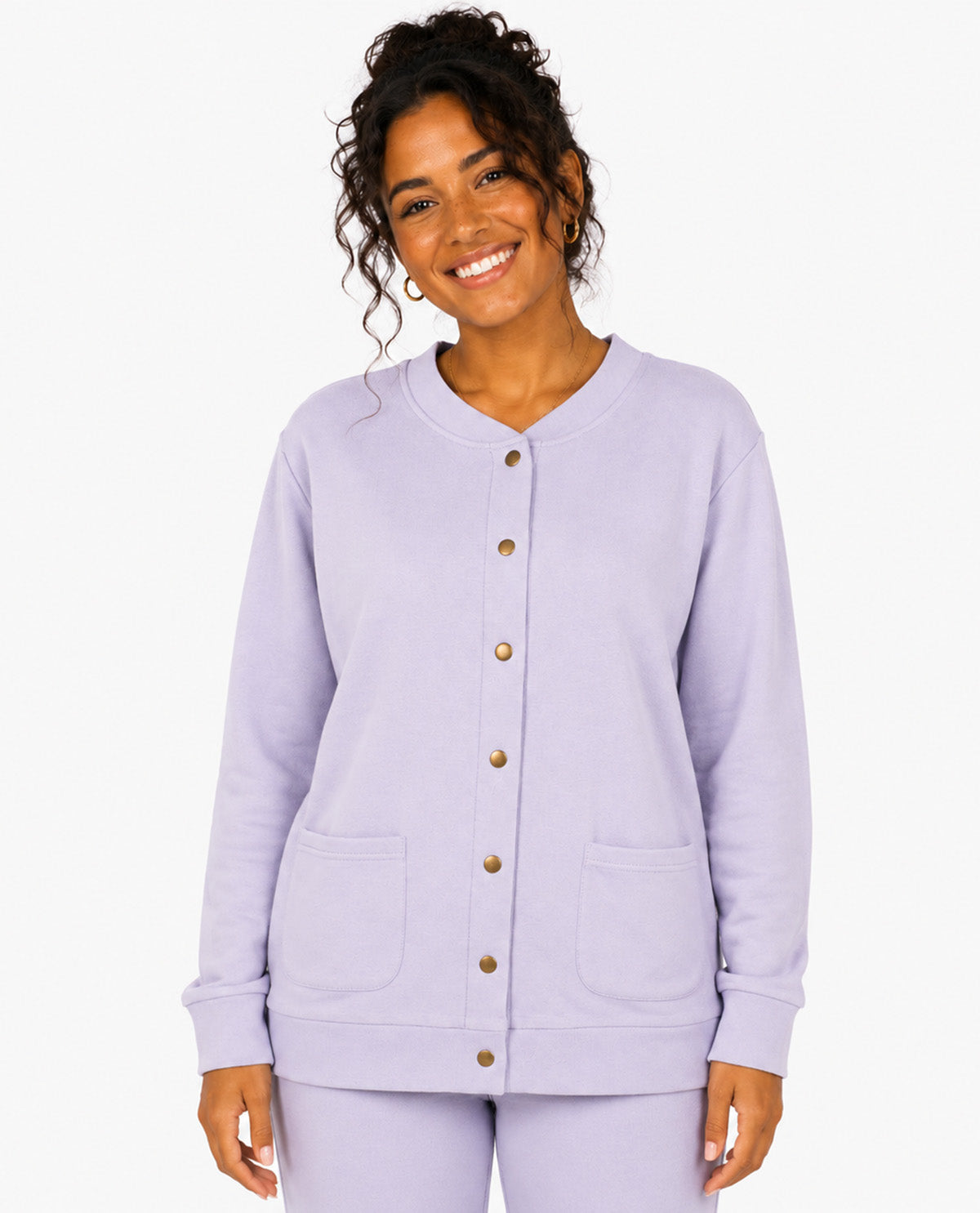 A woman modeling a light lavender cardigan with a button-down front, ribbed collar, cuffs, and hem, and two front patch pockets. She is also wearing matching lavender pants against a clean white background.