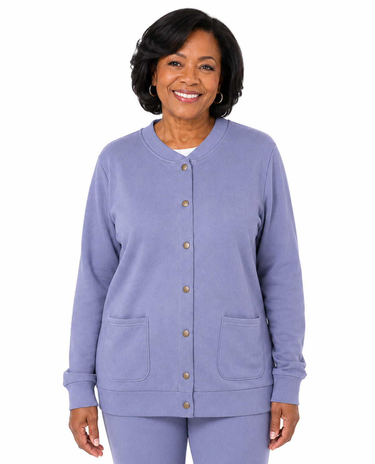A smiling woman wearing a lavender cardigan-style top with front buttons and two front patch pockets, paired with matching pants, against a plain white background.