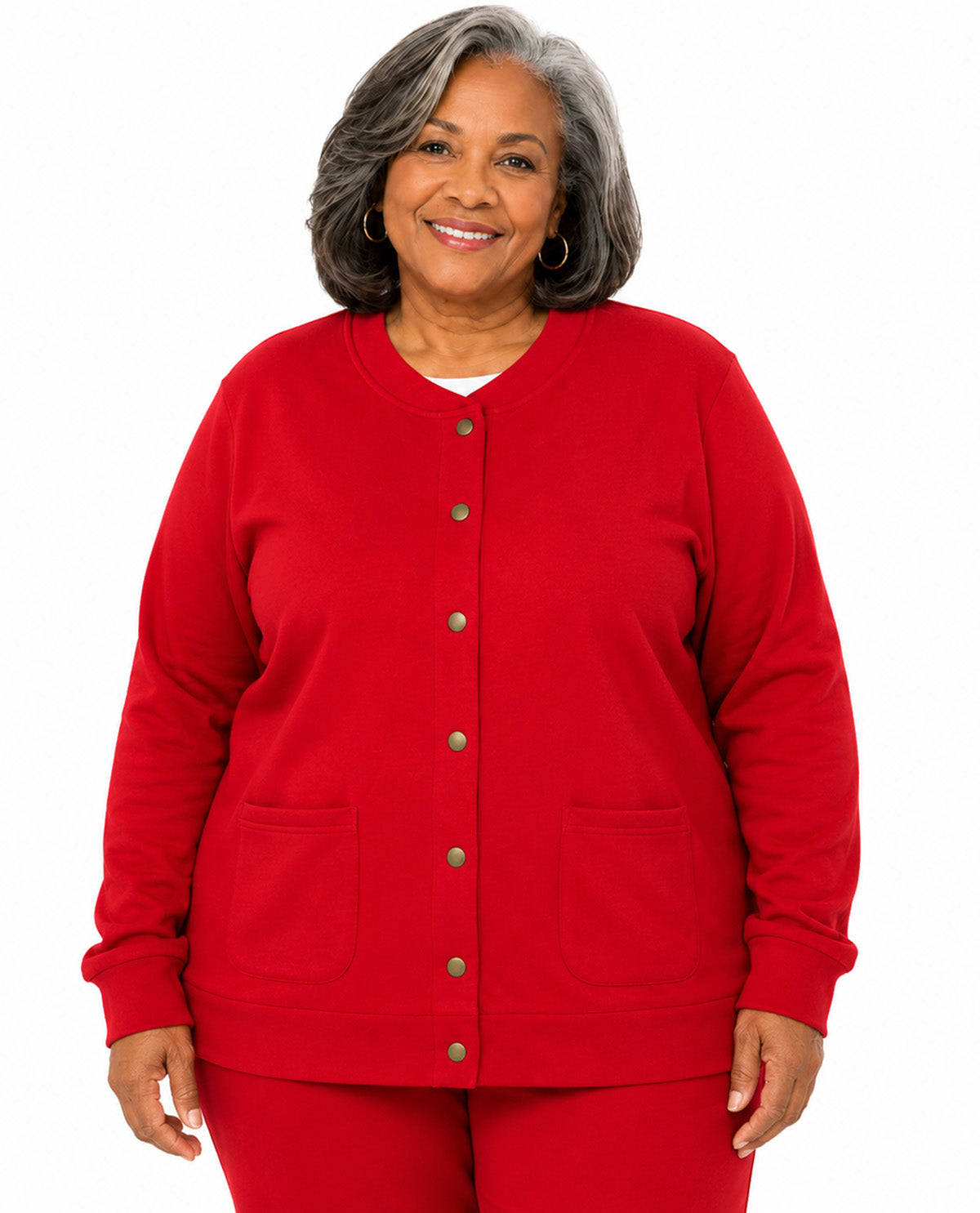 A smiling woman with gray hair wearing a bright red button-front cardigan and matching red pants, photographed against a plain white studio background.