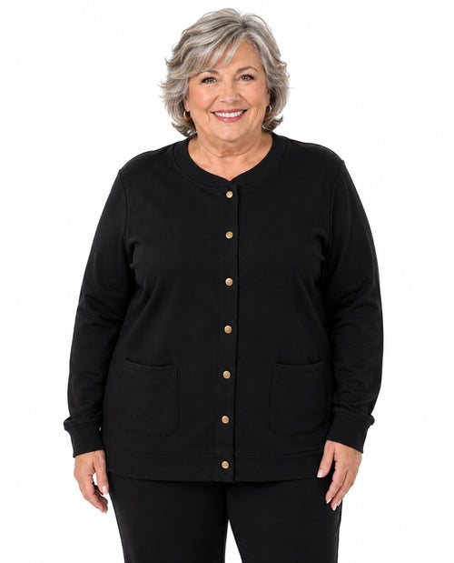 A smiling older woman with short gray hair wearing a black long-sleeve button-front cardigan with two front patch pockets, shown against a plain white studio background.