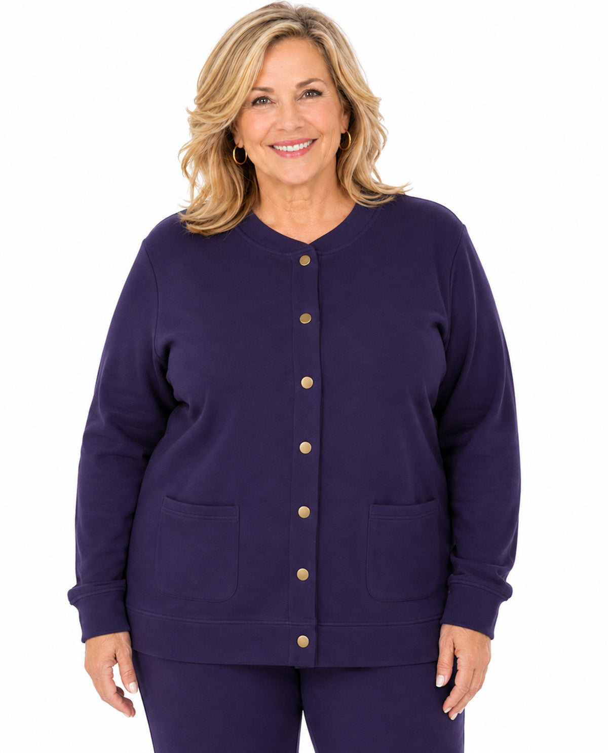A woman modeling a dark purple long-sleeve button-front cardigan with two front patch pockets and matching purple pants, photographed against a plain white background.