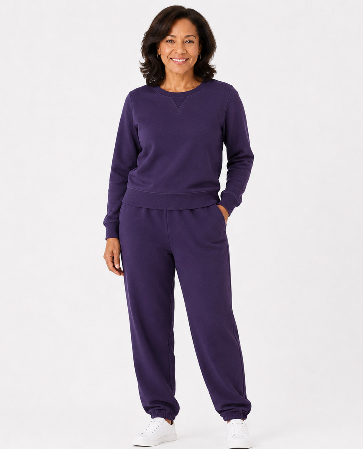 A woman modeling a matching purple sweatshirt and jogger pants set against a plain white studio background.