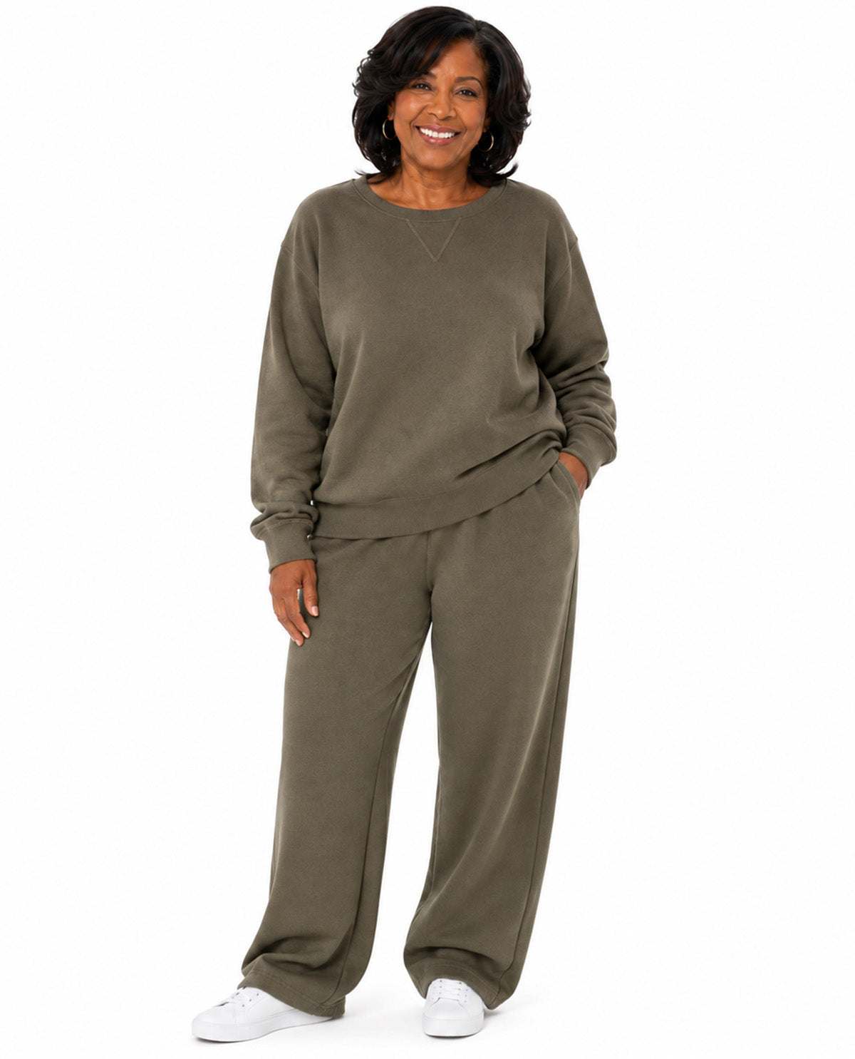 A woman modeling a matching two-piece lounge set consisting of a long-sleeve sweatshirt and wide-leg sweatpants in an olive green color, paired with white sneakers, against a plain white background.