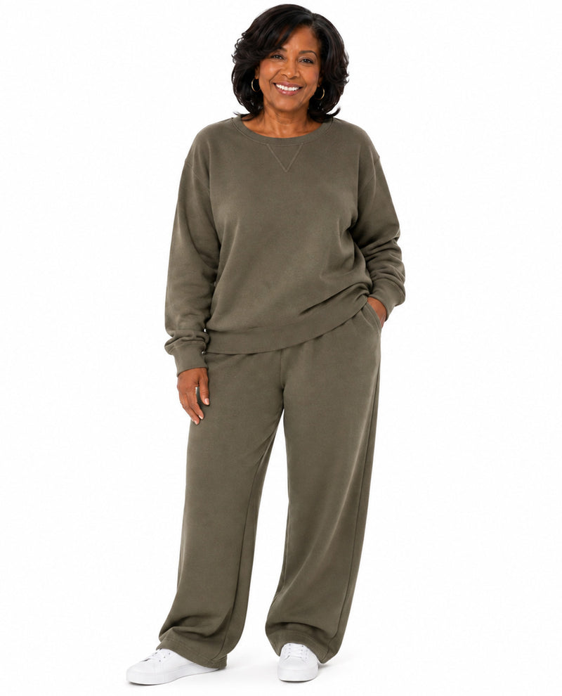 A woman modeling a matching two-piece lounge set consisting of a long-sleeve sweatshirt and wide-leg sweatpants in an olive green color, paired with white sneakers, against a plain white background.