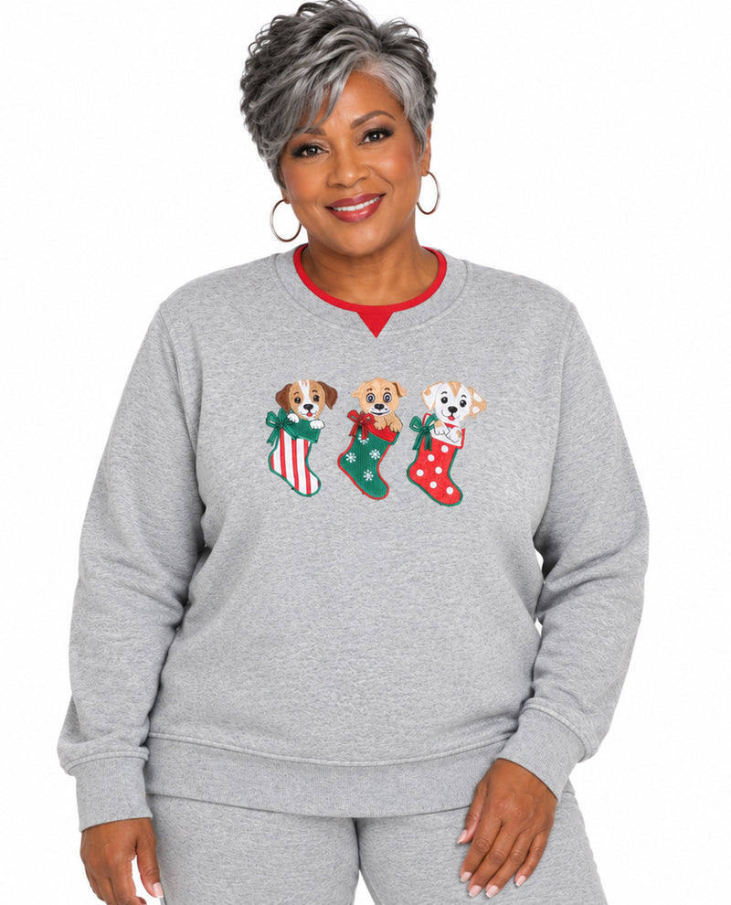 A woman wearing a heather gray crewneck sweatshirt with a graphic of three Dalmatian dogs in Christmas stockings, paired with matching gray sweatpants, against a plain white background.