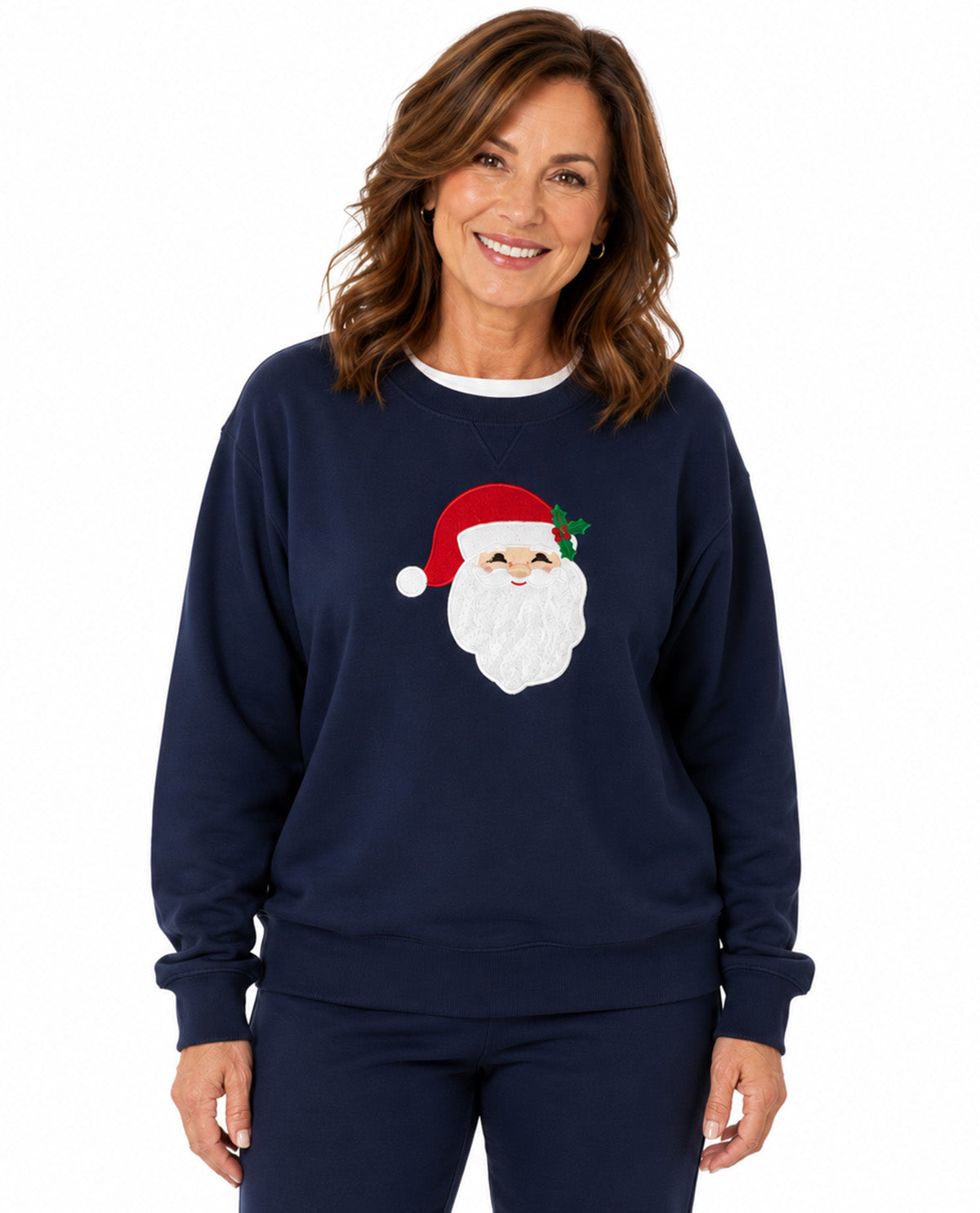 A woman wearing a navy blue crewneck sweatshirt with a graphic of a smiling Santa Claus face on the chest, paired with matching navy pants, against a plain white background.