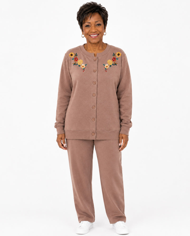 A woman modeling a matching two-piece lounge set in a dusty rose-brown color, featuring a button-front long-sleeve top with colorful floral embroidery on the chest and matching wide-leg pants, against a plain white background.