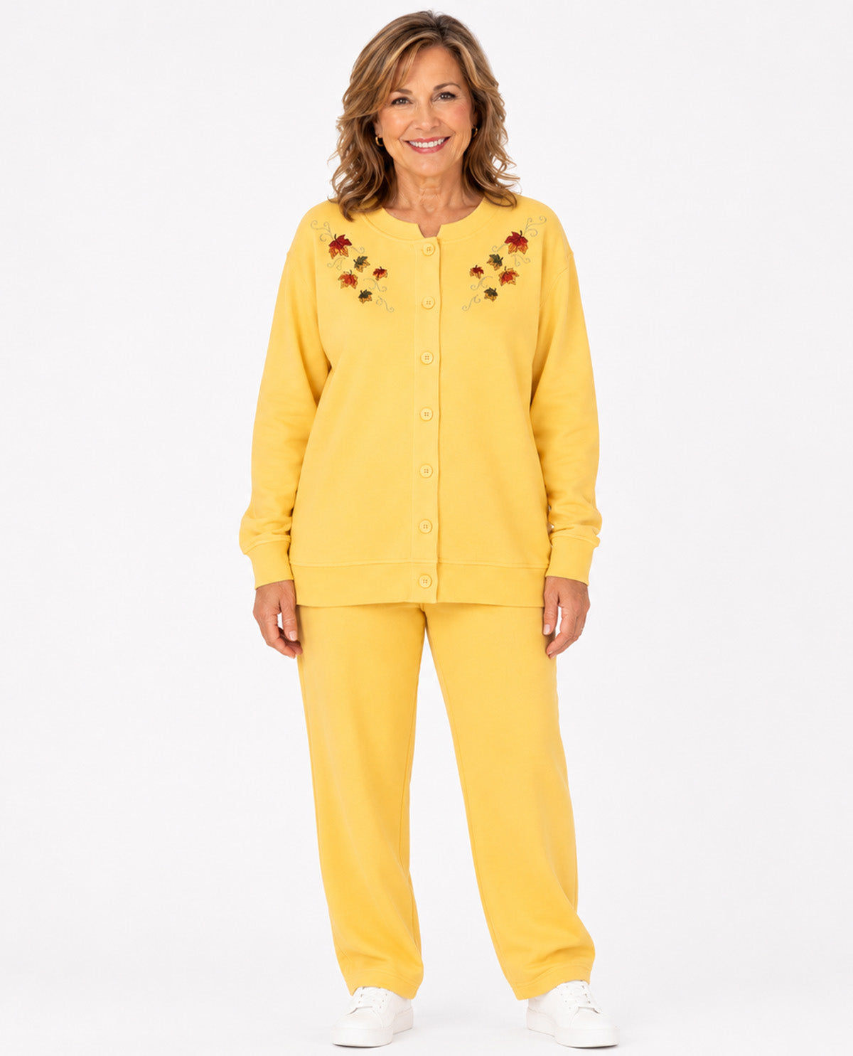 A woman modeling a matching two-piece lounge set consisting of a yellow button-front cardigan with embroidered leaf details on the chest and matching yellow pants, photographed against a plain white studio background.
