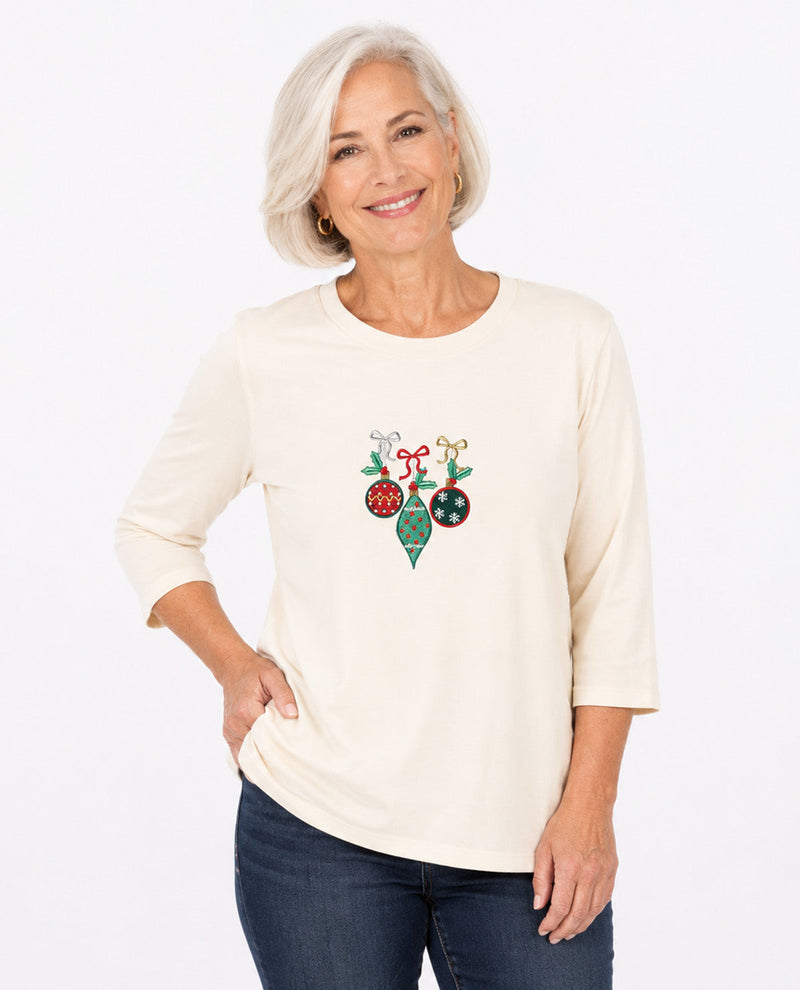 Person wearing an ivory top with Christmas ornaments with a white background