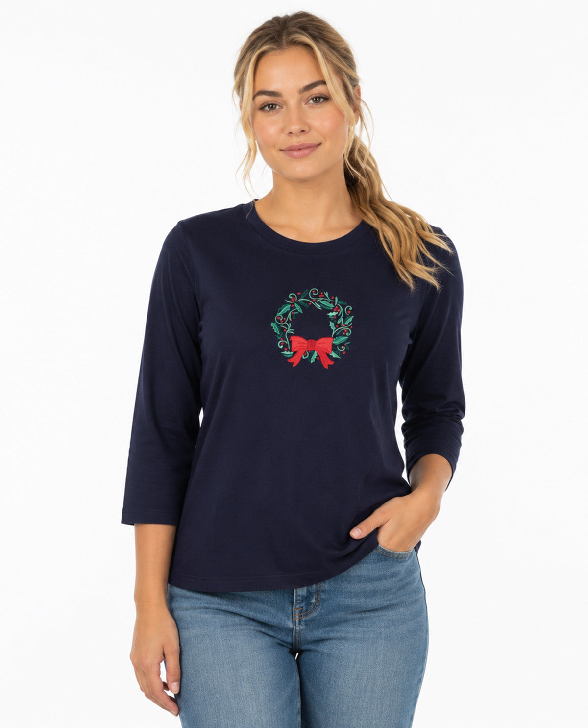 Person wearing a navy top with a Christmas wreath with a white background