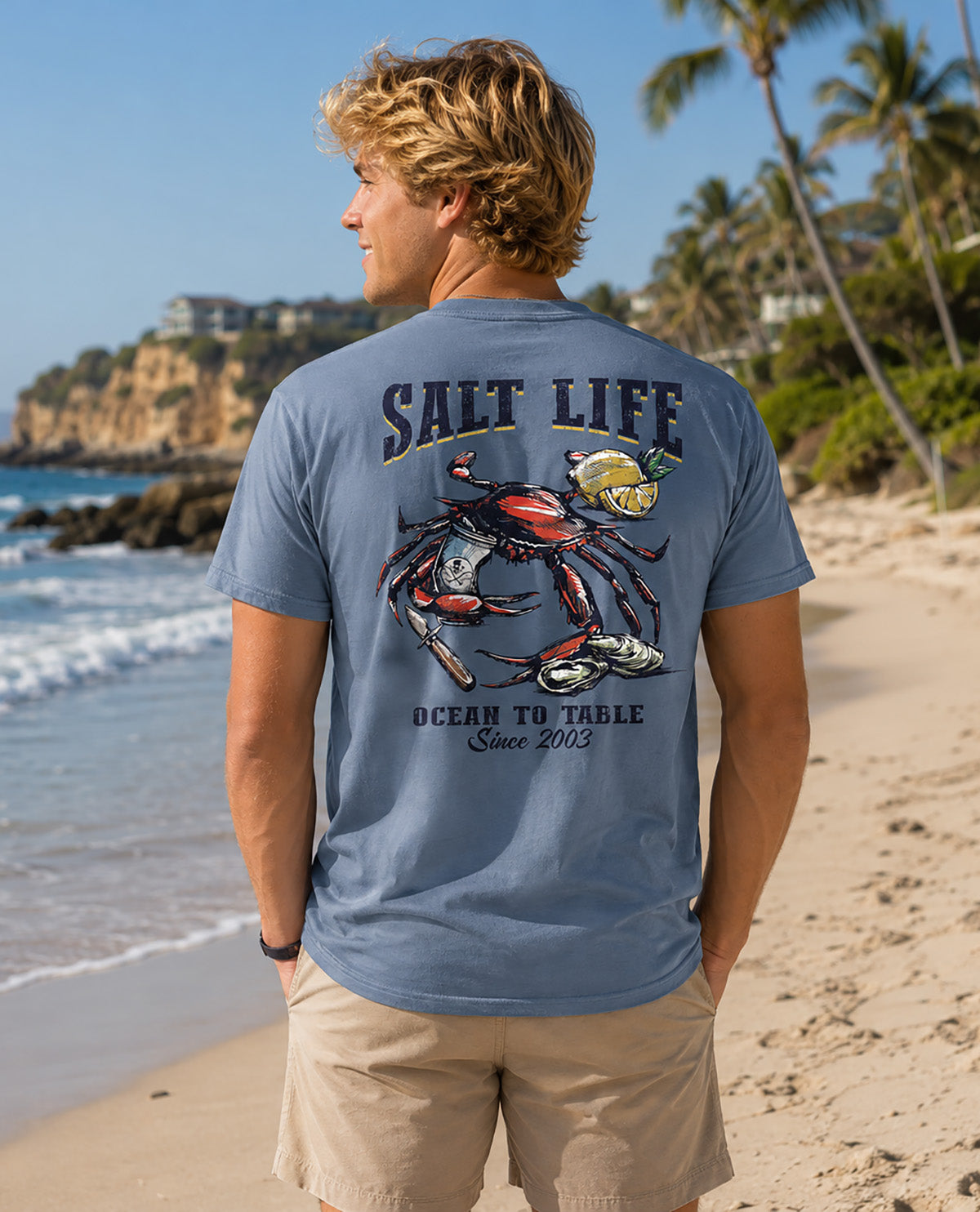 Male model wearing a blue salt life tee with image on back with a crab