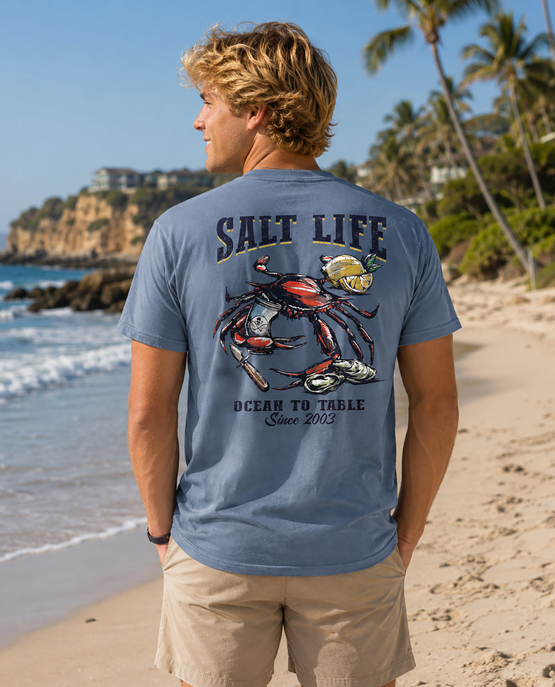 Male model wearing a blue salt life tee with image on back with a crab