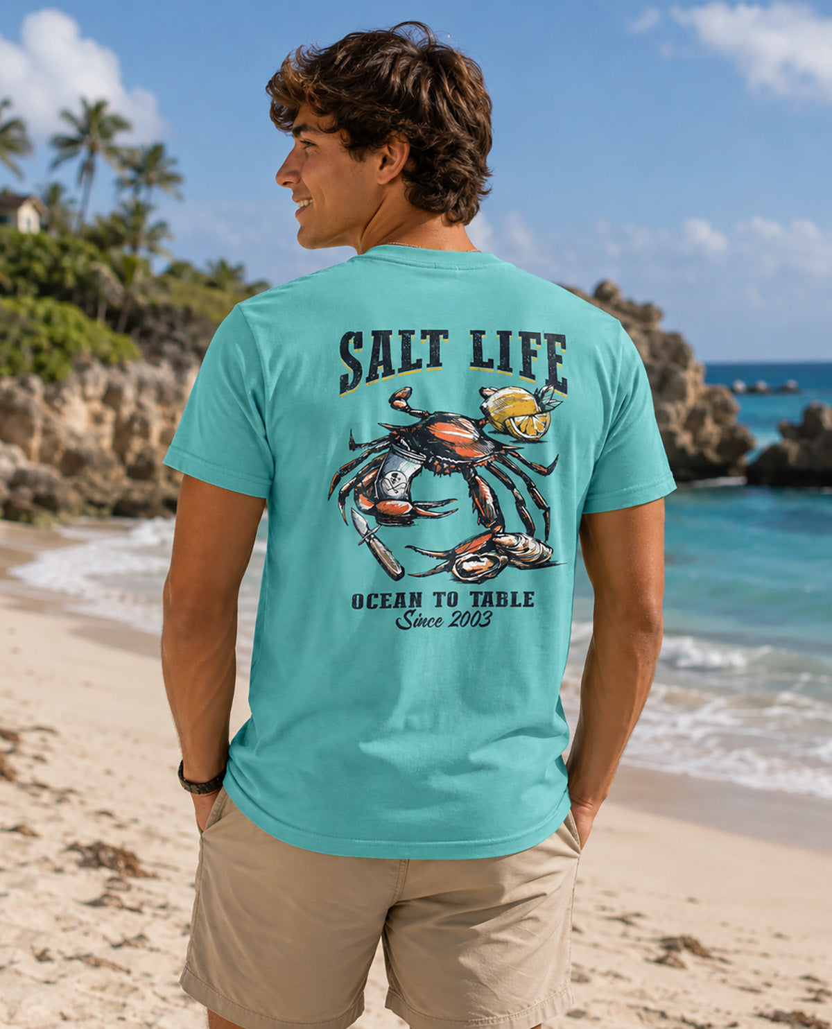 Male model wearing a teal salt life tee with image on back with a crab
